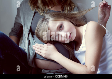 Jeune fille à l'écoute de l'abdomen de la mère Banque D'Images