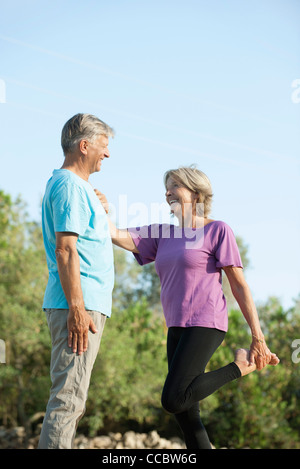 Senior couple outdoors, woman holding sur à l'homme tout en s'étendant Banque D'Images