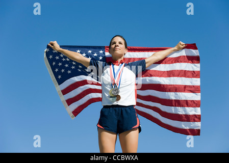 Athlète féminin à l'honneur sur le podium, holding up drapeau Américain Banque D'Images