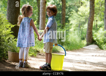 Les enfants se tenant la main sur le chemin dans les bois Banque D'Images