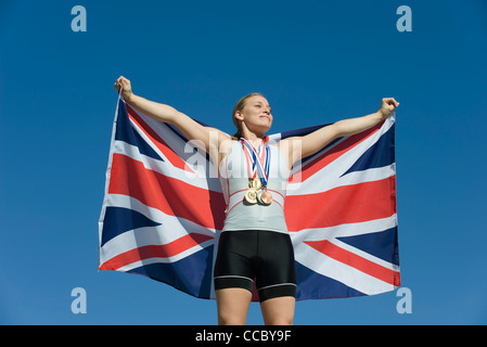 Athlète féminin à l'honneur sur le podium, holding up drapeau britannique Banque D'Images