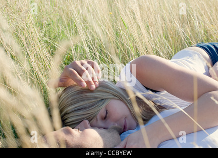 Couple lying together in field of tall grass Banque D'Images