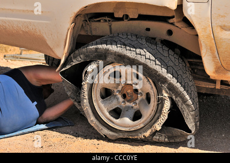 Fixation du pilote blowout tire de véhicule à quatre roues motrices dans le désert du Namib, Namibie Banque D'Images
