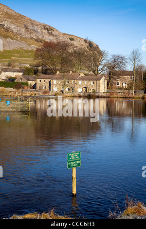 Réflexions de Watersude du crag de Kilnsey, maisons et couleurs de feuilles d'automne dans le lac de pêche de truite, Wharfedale, Yorkshire Dales, Royaume-Uni. Banque D'Images