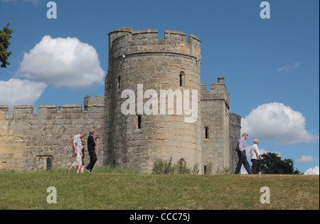 Les visiteurs de marcher sur les douves mur en face de la tour sud-est du 14ème siècle Château de Bodiam, East Sussex, Angleterre, Royaume-Uni. Banque D'Images
