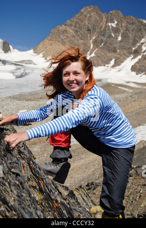 Jeune fille grimpeur fait son chemin à l'apogée de la montagne. Elle est souriant avec bonheur. Banque D'Images