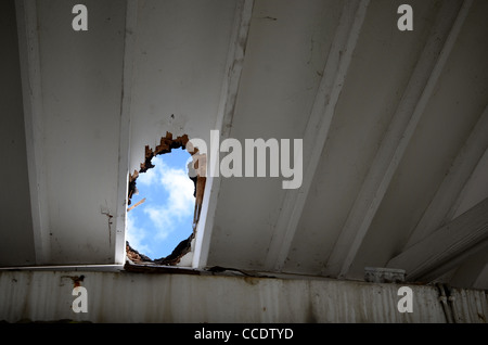 Nuages puffés sur un ciel bleu vu par un grand trou dans un toit de maison. Toit endommagé en raison de fortes précipitations. Banque D'Images