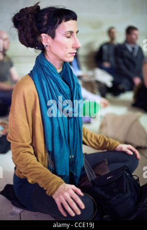 Une femme médite silencieusement dans le cadre d'une méditation flash mob dans la grande cour du British Museum Banque D'Images