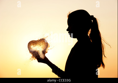 Indian girl holding a water balloon burst. Silhouette. L'Inde Banque D'Images