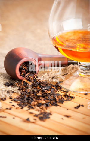 Verre de cognac et le tuyau au tabac sur la table en bois avec de la toile de lin Banque D'Images