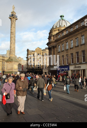 Les gens qui marchent dans Grainger Street avec Grey's Monument situé sur l'arrière-plan Newcastle Angleterre du Nord-Est UK Banque D'Images