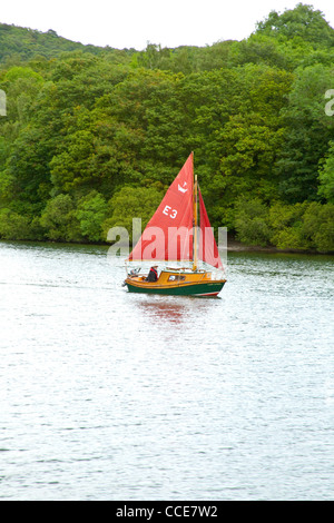 Bateau à voile avec voile rouge sur le lac Windermere, Cumbria, au Royaume-Uni Lake District Banque D'Images