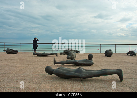 Antony Gormley "masse critique" corps sculpté, De La Warr pavilion, du toit et de la femme en noir contemplant jusqu'à la mer et les nuages de tempête. Banque D'Images