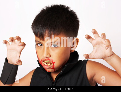 Garçon avec des fausses dents et du sang autour de sa bouche habillés pour Halloween Banque D'Images