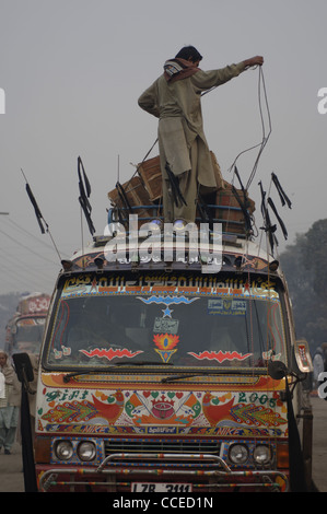 Le chauffeur d'un minibus au départ de la décoration colorée près du Fort de Lahore au Pakistan, les cils vers le bas les sacs sur le toit. Banque D'Images