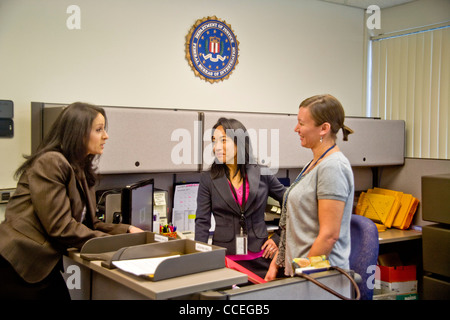 Les trois agents du FBI discuter d'un cas à Santa Ana, CA, bureau. Remarque Filipino-American en centre et logo fbi sur mur. Publié Banque D'Images