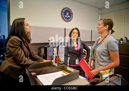 Les trois agents du FBI discuter d'un cas à Santa Ana, CA, bureau. Remarque Filipino-American en centre et logo fbi sur mur. Publié Banque D'Images