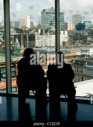 Deux femme assise face à Glasgow city scape à partir de la plate-forme d'observation à travers la fenêtre de verre Banque D'Images