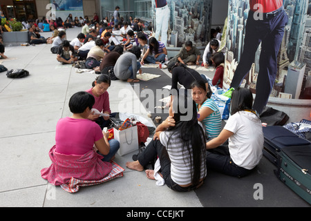Le personnel domestique philippine et chinoise sur leur journée assis en groupes sur le trottoir à l'extérieur du bâtiment de la région administrative spéciale de Hong Kong de la HSBC Banque D'Images
