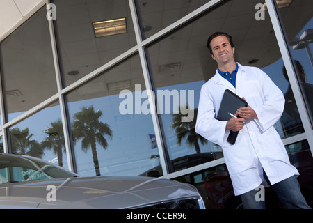 Heureux votre standing in front of car showroom Banque D'Images