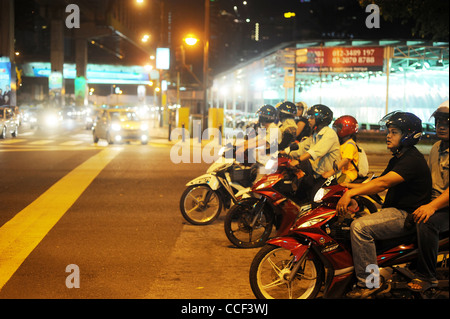 Debout sur les motocyclistes junction à Kuala Lumpur dans la soirée. Banque D'Images