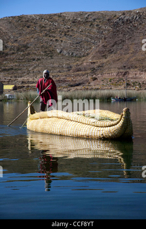 Un homme pousse un Aymara tortora reed sur le radeau du côté bolivien du Lac Titicaca, le lac navigable le plus élevé du monde. Banque D'Images