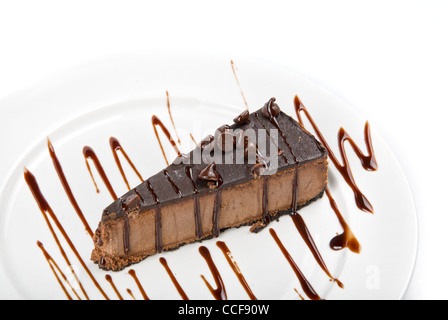 Gâteau au chocolat sur une plaque blanche arrosé de sauce au chocolat sur fond blanc Banque D'Images