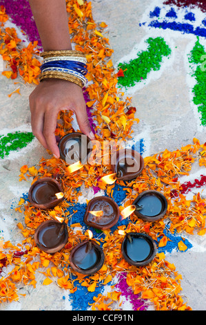 L'Inde girl ajout de lampes à huile à un festival Rangoli design. Puttaparthi, Andhra Pradesh, Inde Banque D'Images