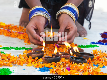 L'Inde girl ajout de lampes à huile à un festival Rangoli design. Puttaparthi, Andhra Pradesh, Inde Banque D'Images