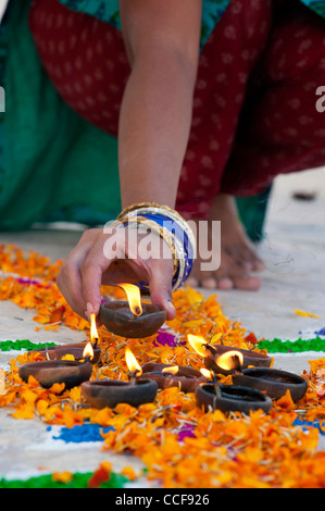 L'Inde girl ajout de lampes à huile à un festival Rangoli design. Puttaparthi, Andhra Pradesh, Inde Banque D'Images