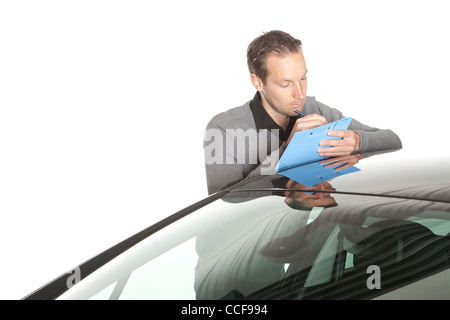 L'évaluateur Mid adult male writing on clipboard tout en s'appuyant sur location Banque D'Images