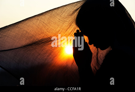 Indian woman praying at sunset couverts par un voile. Silhouette. L'Inde Banque D'Images