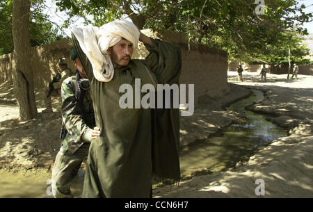 Aug 27, 2004 ; Kandahar, Afghanistan ; un membre de l'Armée nationale afghane vérifie un homme après qu'il a été pris avec deux AK-47's non enregistrés dans un sac. Où les armes confisquées et l'homme laisser aller. Banque D'Images