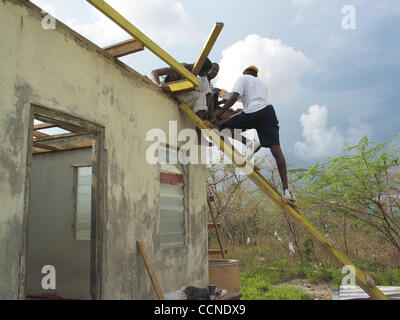 Sep 24, 2004 ; Portland Cottage, la Jamaïque ; réparation voisins le toit de Fredrick Williamson's house, où sa femme, petit-enfant, et deux neveux sont morts au cours de l'ouragan Ivan. Il va quitter la maison, il a passé toute sa vie, dès que le gouvernement crée de nouvelles maisons pour les résidents du village. Banque D'Images