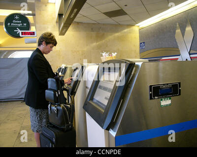 Nov 20, 2004 ; Santa Ana, CA, USA ; un mécène avec bagages utilise un enregistrement libre service machine à l'aéroport afin d'obtenir ses billets d'avion. Les distributeurs de billets automatiques d'accélérer l'embarquement et les passagers sur aux avions. Les billets réservés en ligne sont imprimés sur les machines. Banque D'Images