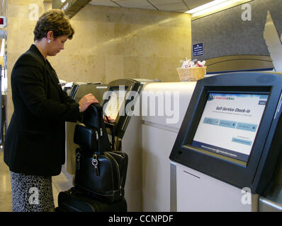 Nov 20, 2004 ; Santa Ana, CA, USA ; un mécène avec bagages utilise un enregistrement libre service machine à l'aéroport afin d'obtenir ses billets d'avion. Les distributeurs de billets automatiques d'accélérer l'embarquement et les passagers sur aux avions. Les billets réservés en ligne sont imprimés sur les machines. Banque D'Images