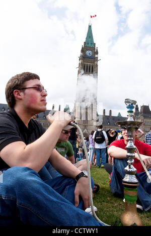 20 avril 2010 : avec la tour de la paix à l'arrière-plan, un jeune homme qui fume du cannabis au cours de la 420 un rassemblement sur la Colline du Parlement à Ottawa, Ontario, Canada. 420, 4:20 ou 4/20 (prononcé quatre-vingt) fait référence à la consommation de cannabis, et par extension, une façon de s'identifier aux drogues cannabis sous Banque D'Images