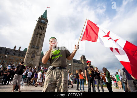 20 avril 2010 : avec la tour de la paix à l'arrière-plan, un jeune homme qui fume du cannabis au cours de la 420 un rassemblement sur la Colline du Parlement à Ottawa, Ontario, Canada. 420, 4:20 ou 4/20 (prononcé quatre-vingt) fait référence à la consommation de cannabis, et par extension, une façon de s'identifier aux drogues cannabis sous Banque D'Images