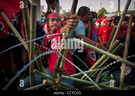 20 avril 2010 - Bangkok, Thaïlande - un manifestant anti-gouvernement tire des morceaux de bambou et de barbelés à l'érigé des barricades sur la ligne "séparation" entre manifestants et l'armée thaïlandaise dans le quartier financier. La tension monte comme le gouvernement thaïlandais des soldats de l'armée déployée et le ri Banque D'Images