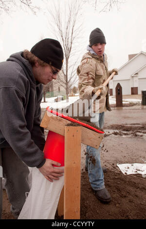 15 mars 2010 - Oxbow, Dakota du Nord, USA - Lukas Paulson, gauche, et Jared Schwandt remplir des sacs de sable à un d'Oxbow, Dakota du Nord Accueil Lundi, 15 mars 2010 à titre de bénévoles construire une digue de protection à partir de la crue des eaux de la rivière Rouge. Une grande partie de la ville d'Oxbow a été inondée au cours record de riv Rouge Banque D'Images