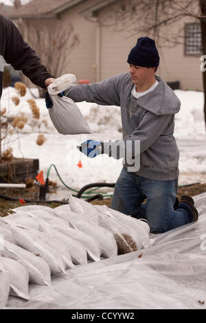 15 mars 2010 - Oxbow, Dakota du Nord, USA - Propriétaires Joe Sauvageau ajoute des sacs d'une digue de terre derrière son d'Oxbow, Dakota du Nord Accueil Lundi, 15 mars 2010 à protéger de crue des eaux de la rivière Rouge. Une grande partie de la ville d'Oxbow a été inondée au cours record de débordement de la rivière Rouge Banque D'Images