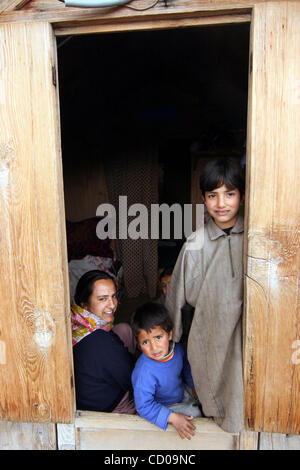 Les enfants et leur mère à travers la fenêtre de leur maison sur les rives du lac Dal à Srinagar, capitale d'été du Cachemire indien. Une fois connu pour son immensité et ses eaux cristallines, le lac Dal est passé de 25 km2 à 12 km2 en raison d'empiétements illégaux et ris Banque D'Images