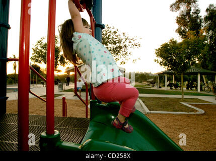 Novembre 19, 2008 Spring Valley, CA  OLIVIA DI BERNARDO, 2, de Spring Valley, balançoires à l'équipement de jeu à Lamar Street Park de Spring Valley. Son père, Monty, dit qu'ils doivent 'co-exister avec les personnes de passage qui se rassemblent à la table de pique-nique couverte (en arrière-plan) et d'autres domaines de l'égalité Banque D'Images