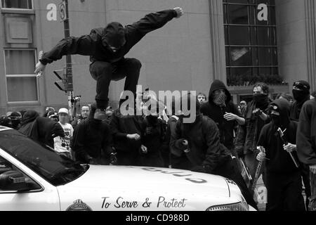 Jun 25, 2010 - Toronto, Ontario, Canada - Black Bloc protestataire de sauter sur une voiture de police pendant le sommet du G20 de protestation contre le centre-ville de Toronto. Bien que la réunion du G20 s'est passé à Toronto le juin 2010, le Black Bloc sont descendus dans la rue. Le groupe de jeunes vêtus de chandails à capuchon de couleur foncée, com Banque D'Images