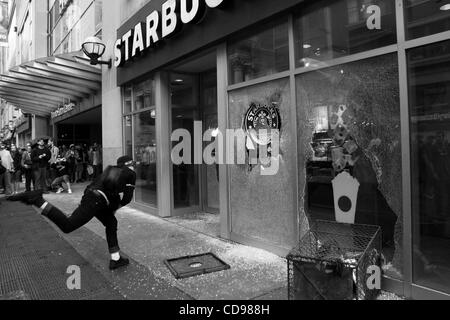 Jun 25, 2010 - Toronto, Ontario, Canada - Black Bloc protestataire smashing un café Starbucks windows au cours de l'émeute dans les rues de Toronto. Bien que la réunion du G20 s'est passé à Toronto le juin 2010, le Black Bloc sont descendus dans la rue. Le groupe de jeunes vêtus de chandails à capuchon de couleur foncée, com Banque D'Images