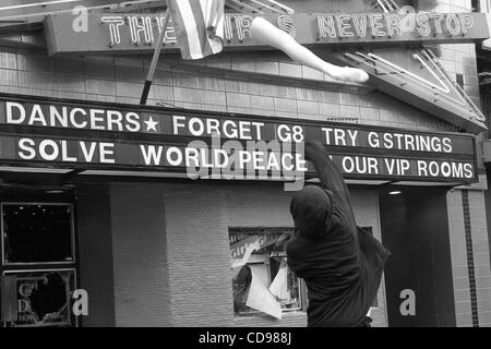 Jun 25, 2010 - Toronto, Ontario, Canada - Black Bloc manifestant jetant une jambe de mannequin à un strip club signe en centre-ville de Toronto pendant le Sommet du G20 de protestation. Bien que la réunion du G20 s'est passé à Toronto le juin 2010, le Black Bloc sont descendus dans la rue. Le groupe de jeunes vêtus de couleur sombre hoode Banque D'Images