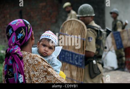 Jul 28, 2010 - Cachemire, Srinagar, Inde - les femmes musulmanes du cachemire avec son enfant à pied comme soldats paramilitaires indiennes montent la garde lors d'une manifestation anti-Inde à Srinagar, la capitale d'été du Cachemire indien. Depuis le 11 juin cette année, 17 personnes sont mortes et des décès sont attribués aux forces de sécurité indiennes Banque D'Images