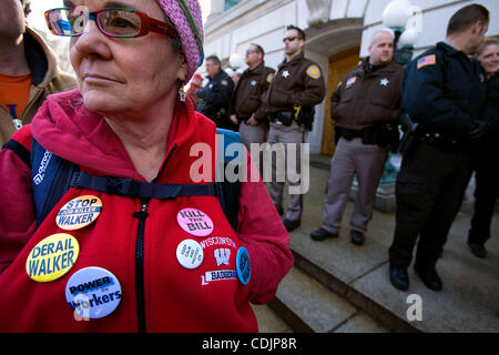 MADISON, WI - mars 1, 2011 : orné de boutons de protestation, Beth Horikawa de Madison, WI se tient avec les manifestants face à une ligne de policiers à l'entrée de la rue King à le capitole de Madison, WI, mardi. Guillaume est un professeur d'école à temps partiel. Une ligne de bureau de police Banque D'Images