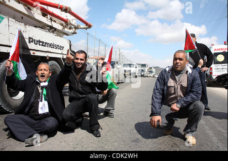 Les hommes palestiniens vague leur drapeau national, assis et block Road 60, qui relie Jérusalem et Hébron et est utilisé par les Palestiniens et les colons juifs, sur Mars 08,2011 à Beit Omar, près de la ville de Cisjordanie d'Hébron et la colonie de Kiriat Arba. Photo par Najeh Hashlamoun . Banque D'Images