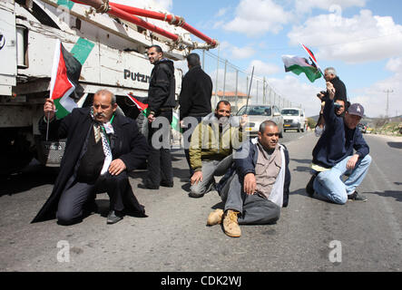 Les hommes palestiniens vague leur drapeau national, assis et block Road 60, qui relie Jérusalem et Hébron et est utilisé par les Palestiniens et les colons juifs, sur Mars 08,2011 à Beit Omar, près de la ville de Cisjordanie d'Hébron et la colonie de Kiriat Arba. Photo par Najeh Hashlamoun . Banque D'Images